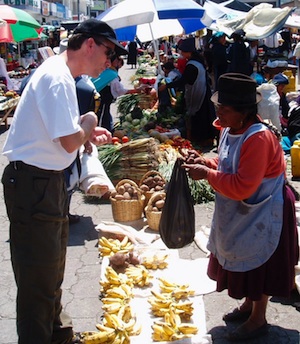 A climber purchasing food in a traditional Ecuadorian market.
